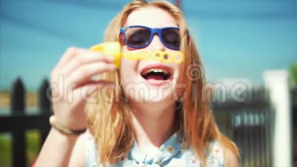 快乐的微笑少女白种人的外表微笑的看着相机在夏天的户外吹肥皂泡视频的预览图
