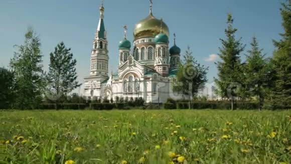 乌斯彭斯基大教堂在奥姆斯克绿色草坪背景与黄色蒲公英视频的预览图