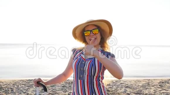 快乐的年轻女子在度假时提着一个手提箱竖起大拇指视频的预览图