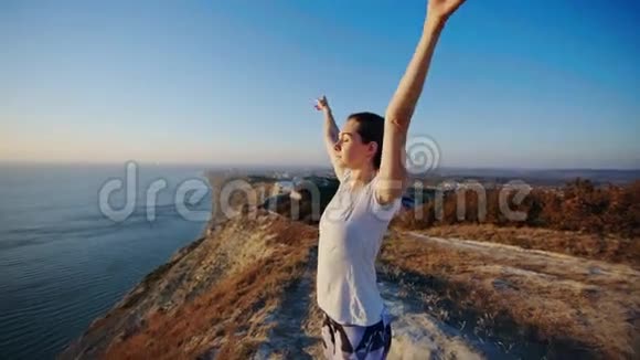 女孩站在悬崖上举起双手视频的预览图