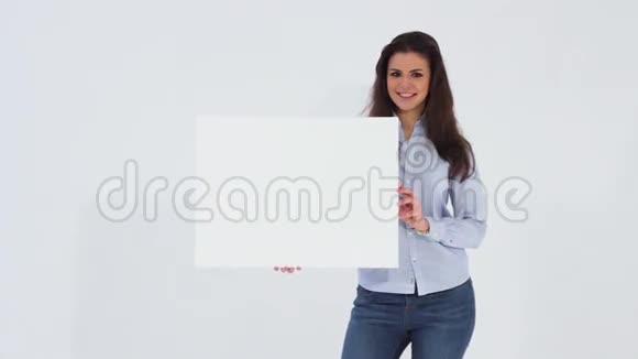 微笑着美丽的女孩看着相机拿着一面空白的白色横幅视频的预览图