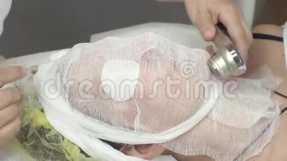 美容师在美容店里用起重设备对成年妇女进行面部护理视频的预览图
