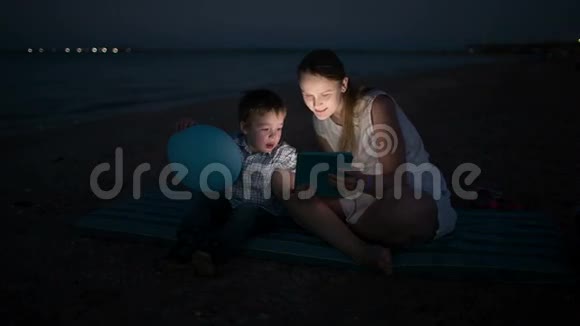妈妈和儿子晚上坐在海边视频的预览图