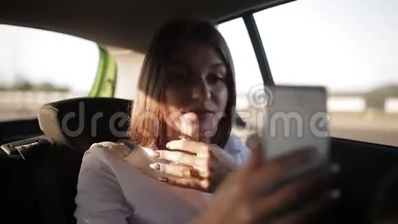 一位漂亮的商务女性坐出租车去参加一个重要的会议并与同事一起使用视频的预览图