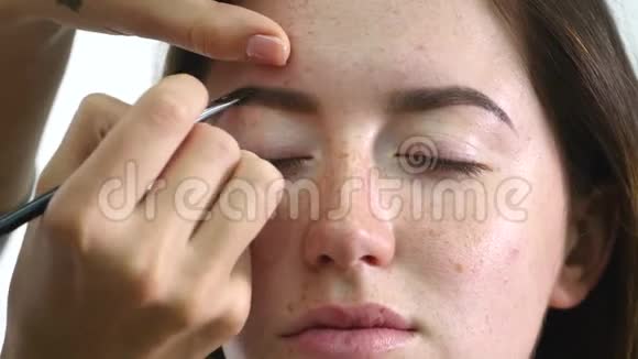 化妆师画一个年轻女孩的眉毛深色专业油漆视频的预览图