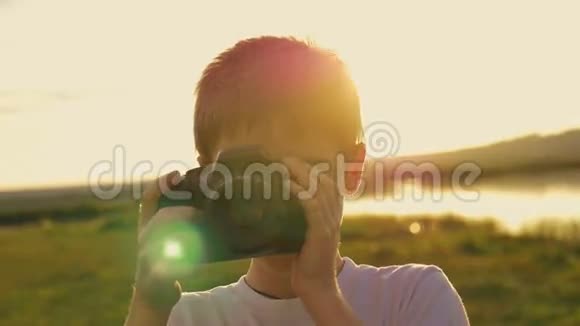 傍晚时分男孩在湖的岸边拍摄母亲的照片视频的预览图