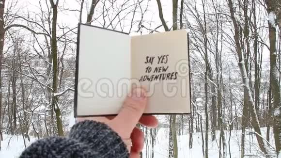 手拿着一本铭文的书对冬天森林背景下的新冒险说是视频的预览图