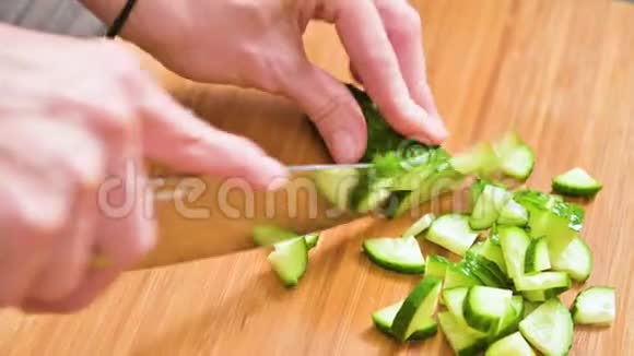 一只雌性的手在木切割板上切一刀黄瓜做沙拉家庭厨房健康视频的预览图