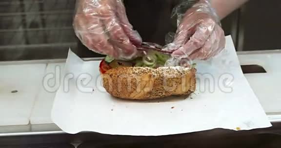穿透明手套的女人在当地快餐特写镜头上准备三明治在露天加新鲜蔬菜视频的预览图