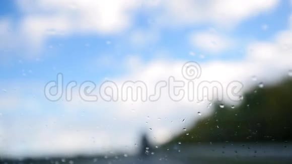 夏季公路在雨天离焦背景挡风玻璃上的水滴视频的预览图