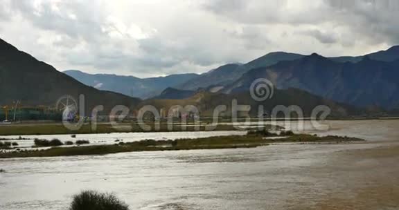 拉萨河与遥远的城市建筑乌云团团滚过西藏山顶视频的预览图