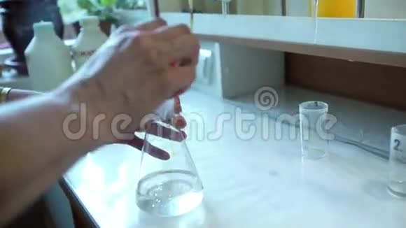 手套中的手在实验室的烧瓶中混合粉红色液体和黄色液体视频的预览图