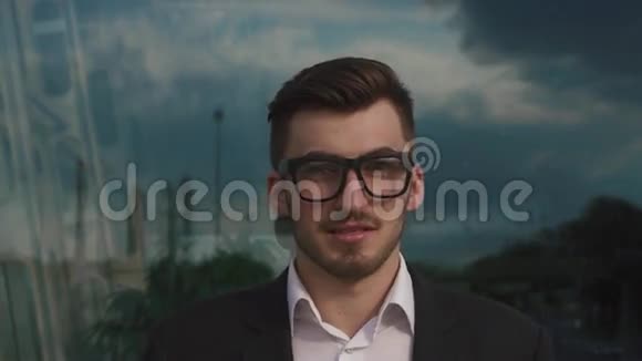 特写一张自信英俊优雅的商人用眼镜盯着相机室外机场背景视频的预览图