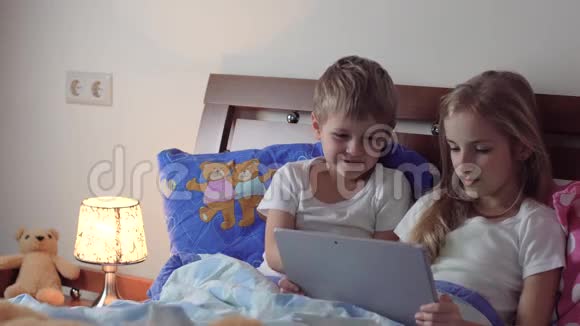 孩子们在床上玩平板电脑视频的预览图
