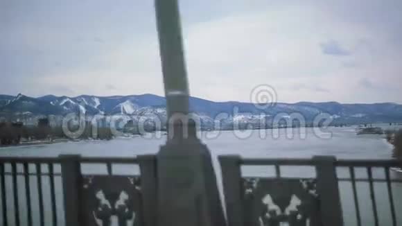 汽车在宽阔的河面上行驶以雪山观景建筑物旅行视频的预览图