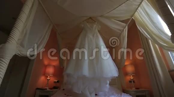 白色蕾丝婚纱挂在衣架上筹备婚礼视频的预览图
