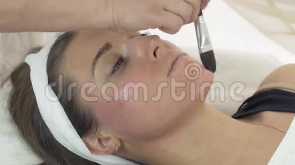 美容师的双手在美容院的女孩脸上贴着润肤露视频的预览图