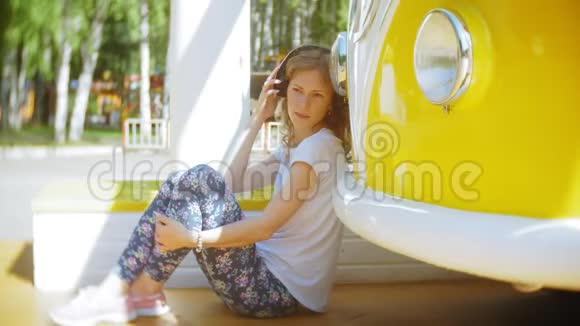 年轻女子在户外乘坐黄色马车用智能手机听耳机音乐放松享受概念视频的预览图