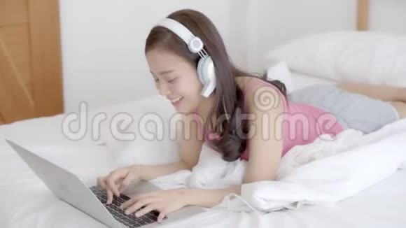 美丽的亚洲年轻女子躺在床上用笔记本电脑显示视频通话在家里的卧室里聊天视频的预览图