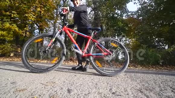 秋天公园里骑自行车的年轻女子近距离拍摄慢动作视频的预览图