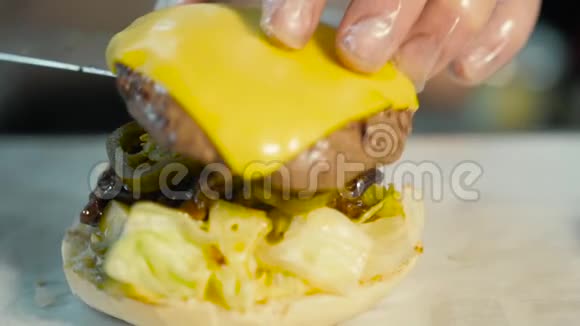 厨师在汉堡上添加配料准备和制作汉堡包快点吃汉堡视频的预览图