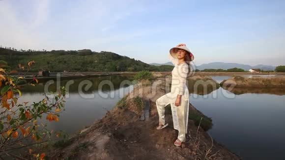 穿着越南服装的金发女孩在池塘之间摆姿势视频的预览图