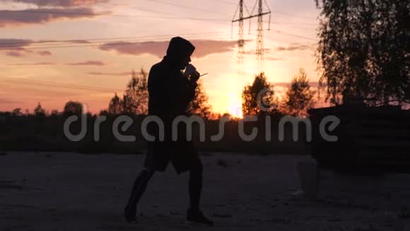 男子拳击手在城市公园踢日落的训练剪影视频的预览图