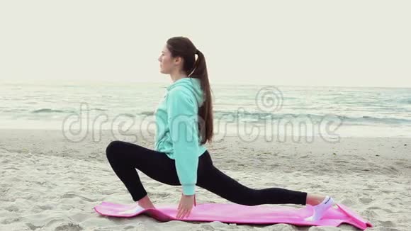 在海边练习瑜伽的年轻女子视频的预览图