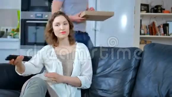 可爱的夫妇在客厅吃比萨饼和看电视披萨太可怕了视频的预览图