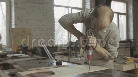 专业的老木匠用钻头在抛光的木板上打洞视频的预览图