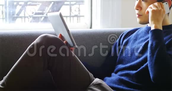 男子在客厅4k使用数码平板电脑时使用手机视频的预览图