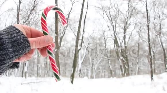 手拿糖果罐头下雪的圣诞风景背景模糊的照片视频的预览图