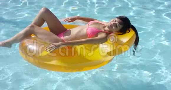 年轻女子在游泳池里晒日光浴视频的预览图