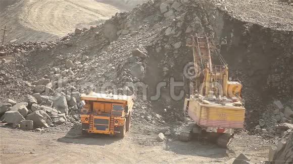 挖掘机将矿石装入采矿自卸汽车中挖掘机将矿石装入铁矿石采石场中视频的预览图