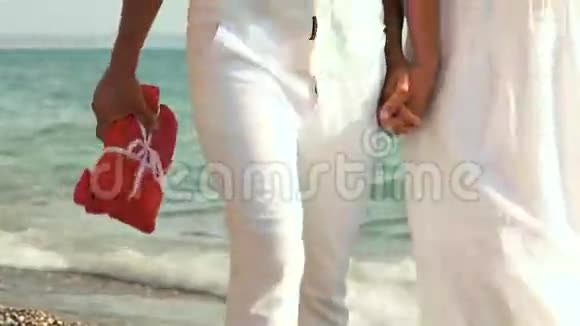 穿着白色衣服的情侣在海滩上散步视频的预览图