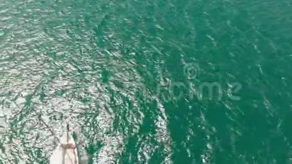 夏天一艘白色的游艇带着帆在蓝色的海里漂浮空中射击视频的预览图