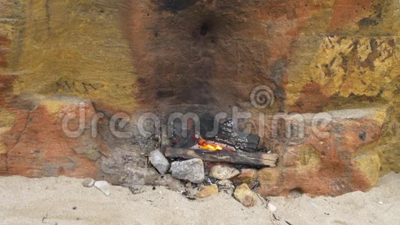 黄壳岩壁附近砂上小火在海滩上野餐视频的预览图