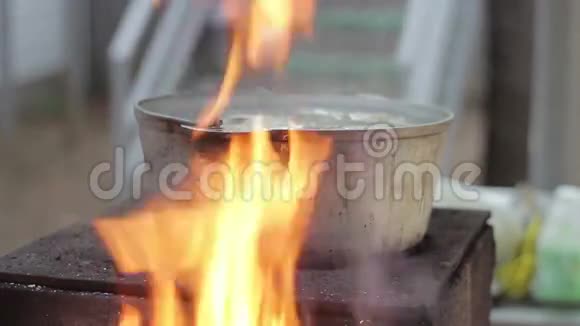 用明火烧柴炉上的金属锅煮鱼汤视频的预览图