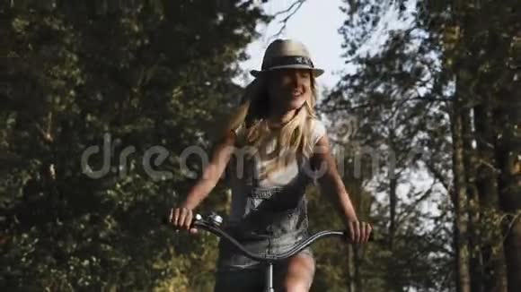 一个年轻的金发女孩穿着复古自行车在田野的路上走视频的预览图