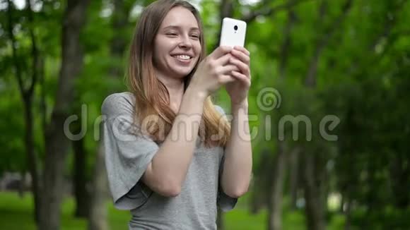 美丽的女人在公园户外使用手机细节视频的预览图