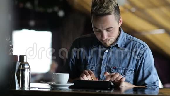 坐在酒吧里的年轻人在平板电脑上打字视频的预览图