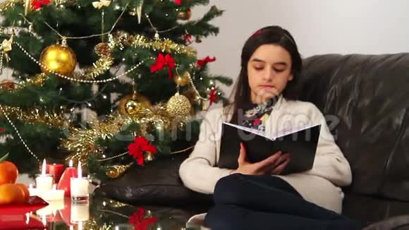 女孩坐在圣诞树旁看书视频的预览图