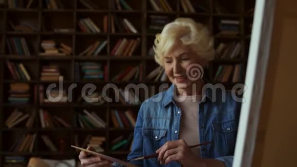 快乐的高级女人在家画画视频的预览图