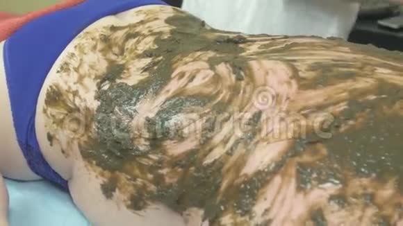 美容师在美容店里把海藻混合物揉在厚厚的女人身上污垢视频的预览图