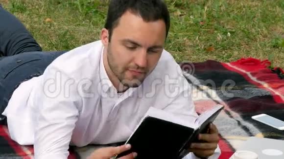 英俊的年轻商人在公园里看书视频的预览图