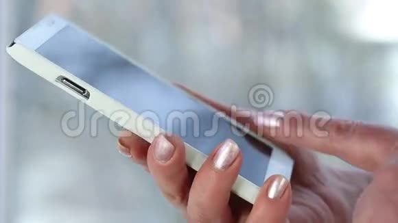 女人拿着白色手机女人在智能手机里看照片视频的预览图