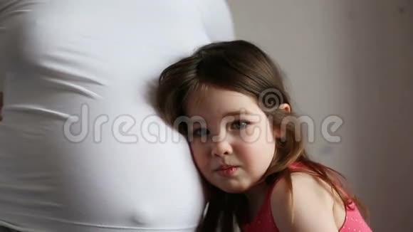 一个女孩听母亲怀孕的肚子视频的预览图