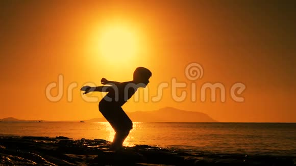 日出时在海滩上跳跃的男孩剪影视频的预览图