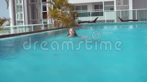 快乐快乐的年轻女子在游泳池的红色游泳套房美丽的晴天绿松石水视频的预览图