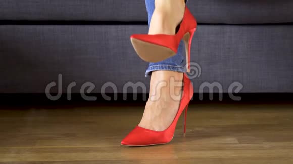 穿着红色高跟鞋坐在沙发上的女人展示和交叉修长的腿视频的预览图